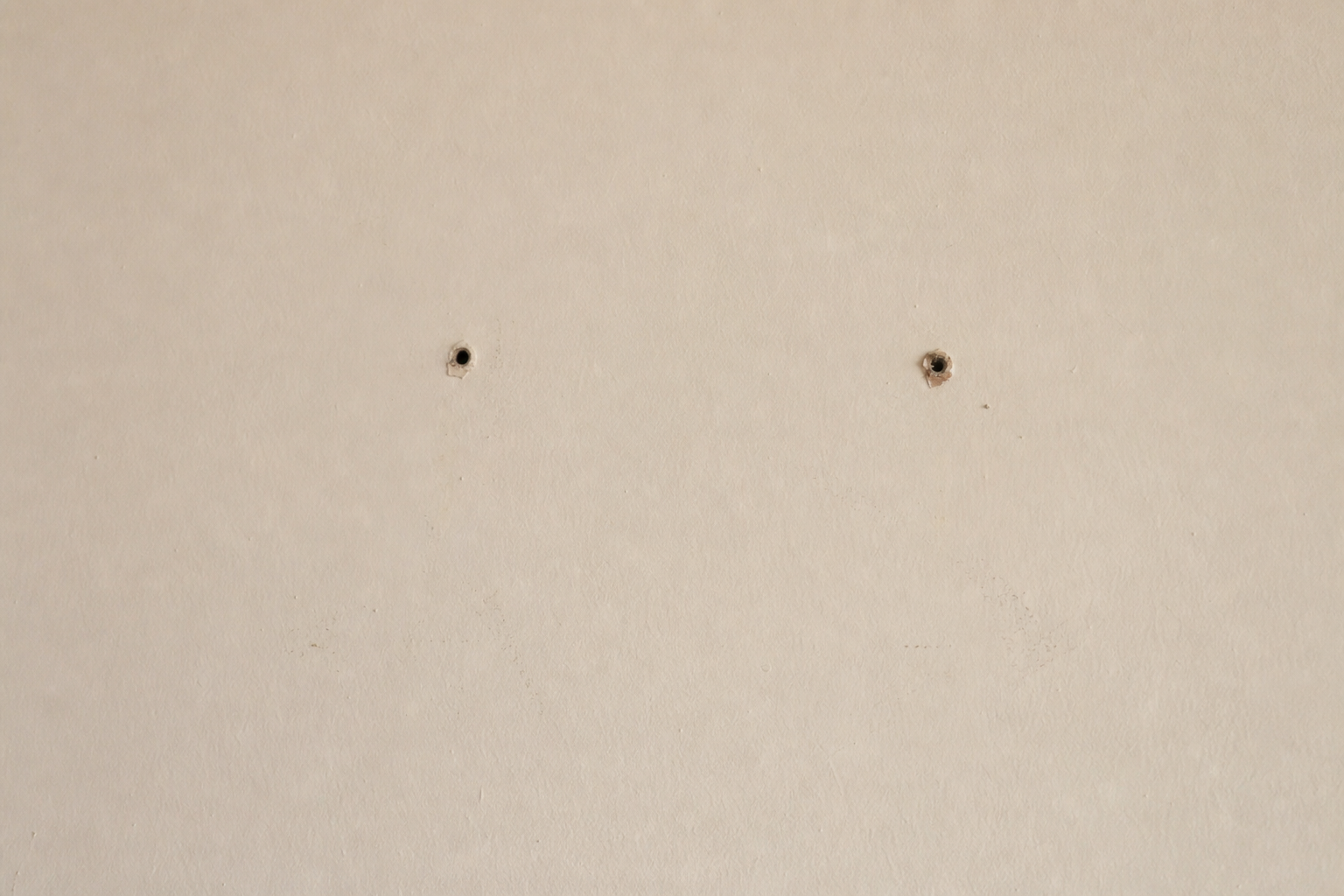 Before repair: small holes and scuffs on cream wall
