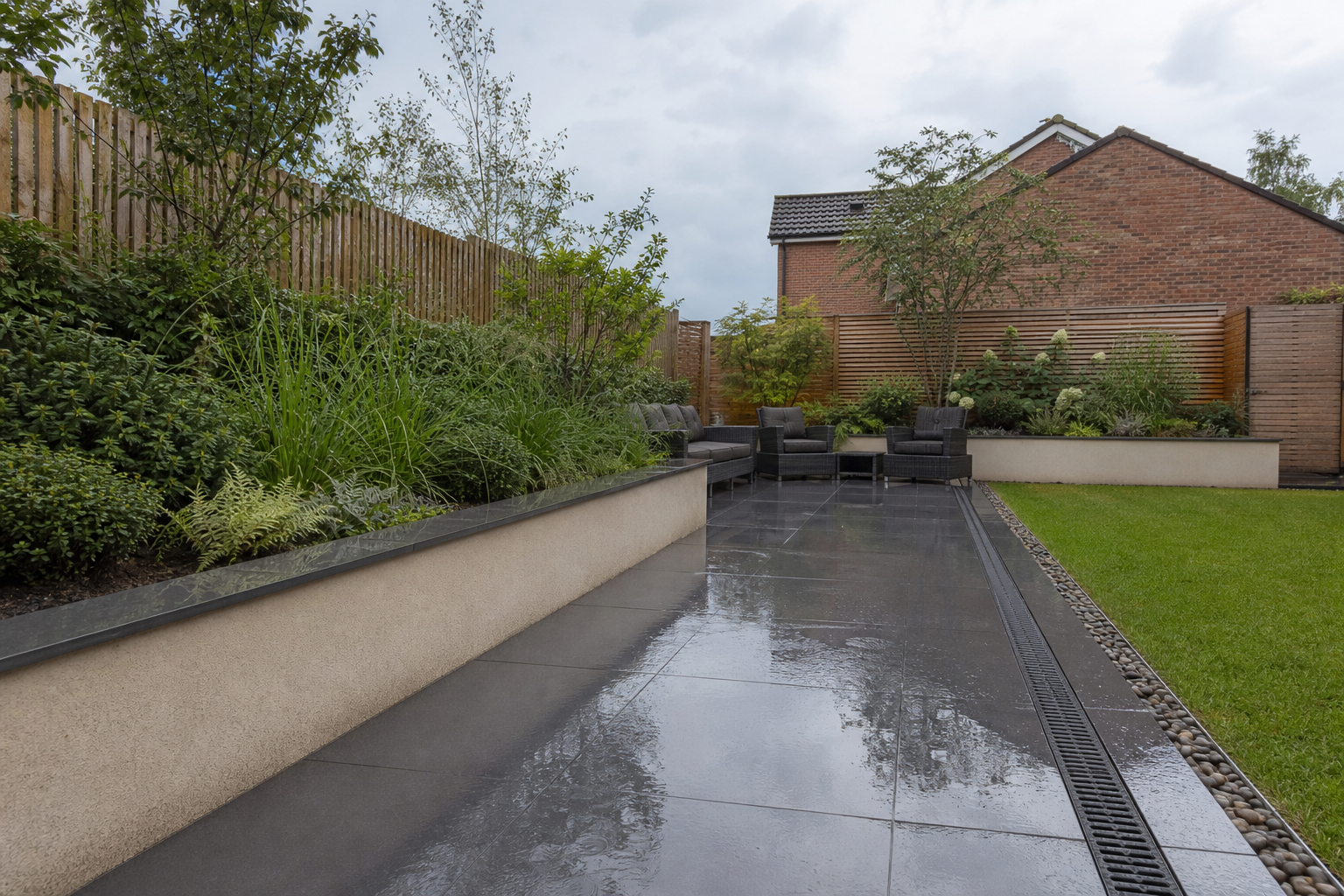 Completed rain-ready garden transformation with wet porcelain patio, drainage channel, raised planting and lawn