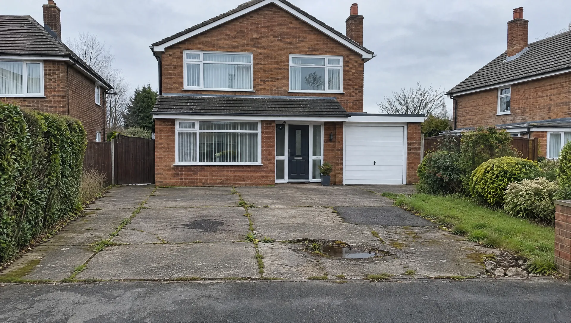 Before: a cracked concrete driveway with weeds and a puddle in front of a brick detached house