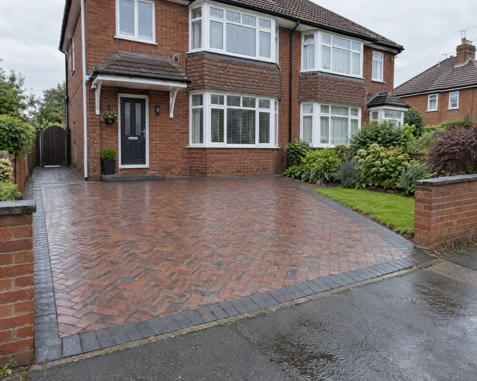 A new brindle block paving driveway with a charcoal border in front of a red-brick semi-detached house