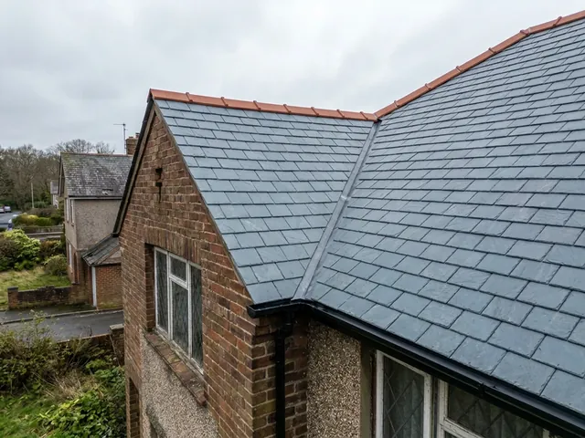 After: the same roof with new slates in straight courses, new ridge tiles and new guttering.